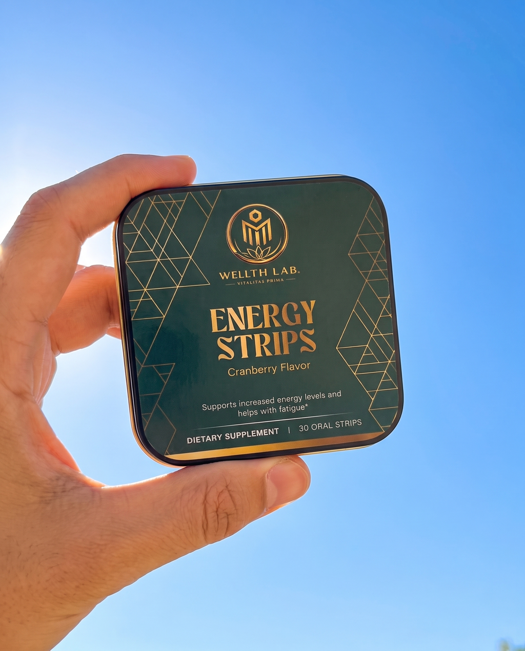 Hand holding Energy Strips tin against blue sky